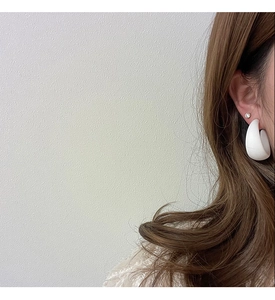 Close-up of matte white C-shaped hoop earrings and stud worn by a model in Korean style