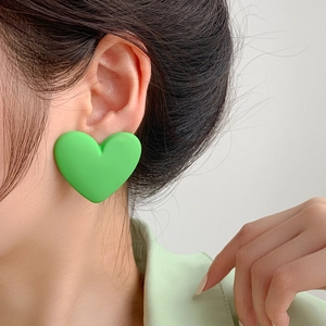 Close-up of matte lime green heart-shaped stud earring worn by a model for size