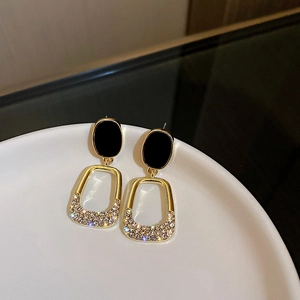 Vintage gold oval earrings with black studs and sparkling zircon inlays shown on ceramic