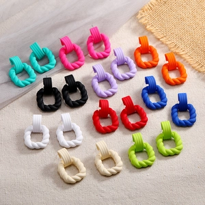 Matrix of matte twisted geometric earrings in various candy colors on a linen backdrop