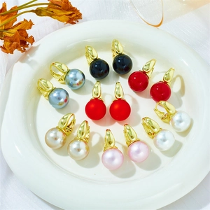 Macro shot of assorted colorful pearls on gold hoop earrings in a ceramic dish