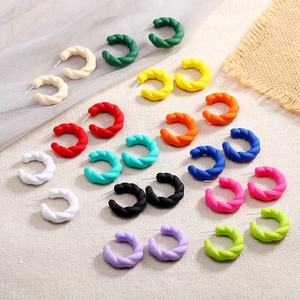 Matte candy-colored twisted C-shape hoop earrings in 12 vibrant colors on textured fabric