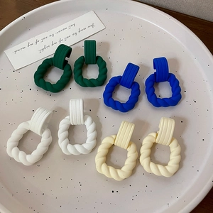 Matte candy-colored geometric twist hoop earrings in dark green, blue, white, and cream