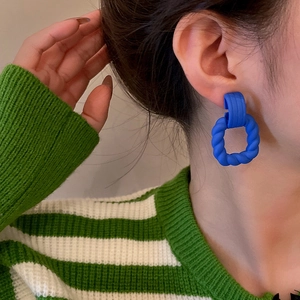 Detail of royal blue matte twisted geometric C-shaped earrings on model