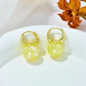 Close-up of golden hoop earrings with iridescent mermaid pearl drops on white silk