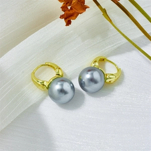 Detailed view of elegant gray pearl drop earrings with golden metal clasps on fabric