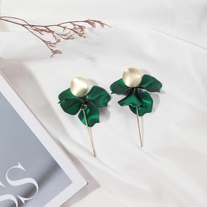 Close-up of matte dark green petal earrings with elegant gold accents on silk fabric