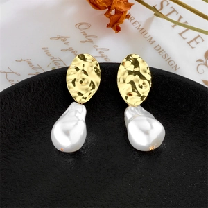 Vintage Baroque irregular pearl earrings with hammered gold metal on black pedestal