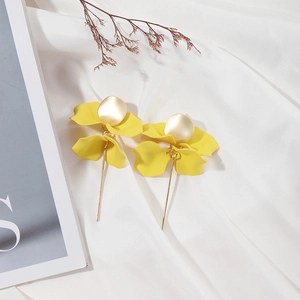 Macro shot of stylish long yellow floral petal earrings with golden matte metal accents