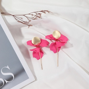 Detail of pink petal tassel earrings with gold circular studs on a white fabric background