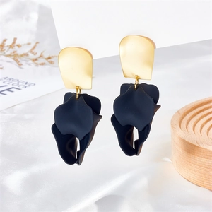 Detail view of fashion petal drop earrings with black matte floral layers on white silk