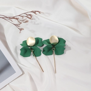 Detailed view of dark green petal earrings with golden matte disk on white silk fabric
