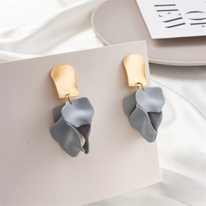 Detail of matte blue-gray petal earrings with wavy golden metal top on beige display card