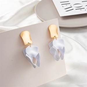 Detail view of white matte petal earrings with gold shield accent on silk fabric