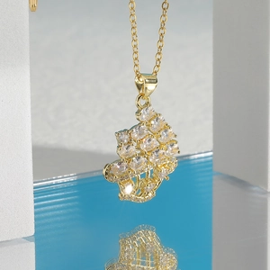Elegante goldene Halskette mit funkelndem Zirkonia-Cluster-Anhänger auf weißem Sockel