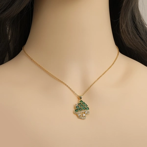 Elegante goldfarbene Halskette mit Baum-Anhänger und grünen Steinen an einem Modell