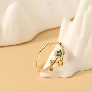 Anillo de estrella dorado con gema verde y circonitas sobre soporte de cerámica