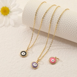 Golden Evil Eye pendant necklaces in black purple and pink enamel on white stands