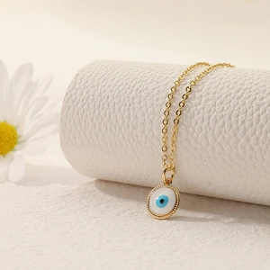 Detail view of gold devil's eye enamel pendant on a white leather jewelry stand