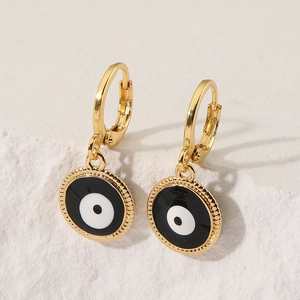 Golden round evil eye earrings with enamel finish and beaded edge on stone background