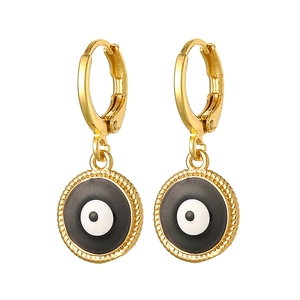 Macro detail of golden Evil Eye drop earrings featuring classic enamel round pendants