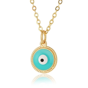 Macro detail of gold evil eye pendant with turquoise enamel and beaded texture
