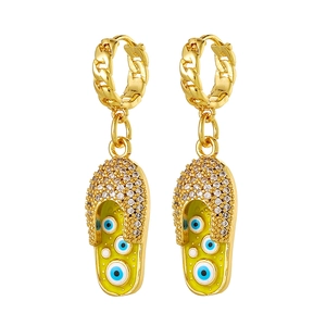 Detail van gouden Cubaanse schakeloorbellen met groene slipper-hangers en blauw boze oog