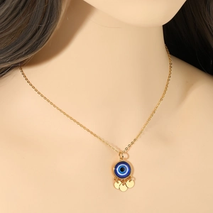 Detail of gold evil eye pendant necklace with three small golden discs on delicate chain