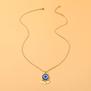 Gold evil eye pendant necklace with blue enamel and small round charms on warm background
