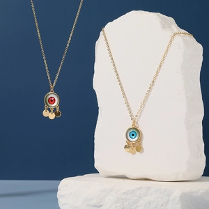 Golden Evil Eye pendant necklace with red and blue crystals on white stone display