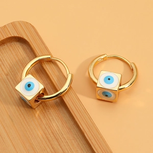 Gold evil eye square charm hoop earrings with blue enamel design on orange background