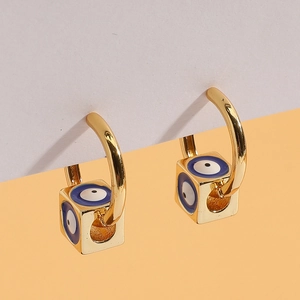Macro detail of gold-plated square evil eye charm drop earrings on minimalist background