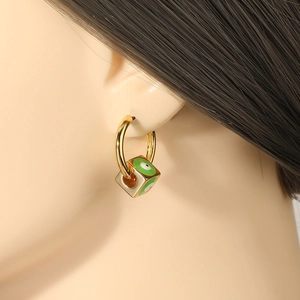 Close-up of golden square Evil Eye earrings with green enamel on model's ear