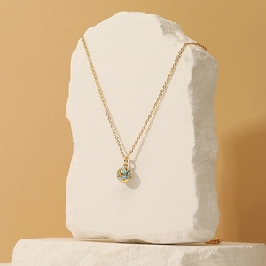 Collier avec pendentif œuf de l'œil bleu doré présenté sur une pierre blanche naturelle