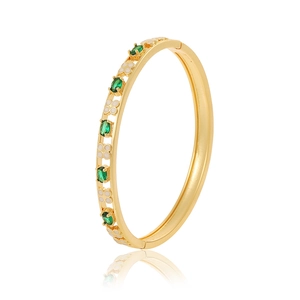 Detail van een vergulde armband met groene edelstenen en witte bloemen in hol ontwerp