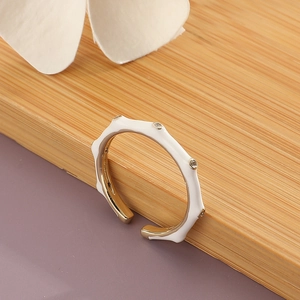 Eleganter goldener Ring mit weißem Emaille-Wellen-Design und Zirkonia auf Holzgrund