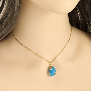 Detail of vintage gold necklace with blue egg pendant and 3D flower embellishments