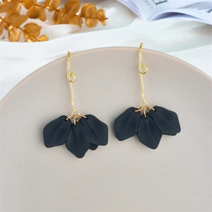 Detail of matte black petal drop earrings with gold hooks on a ceramic dish
