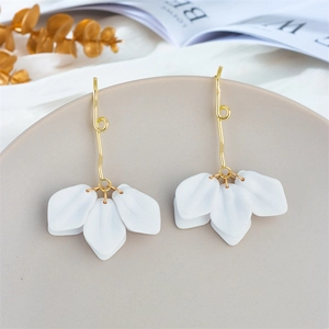 Close-up of white petal earrings with golden hooks on a minimalist gray ceramic tray