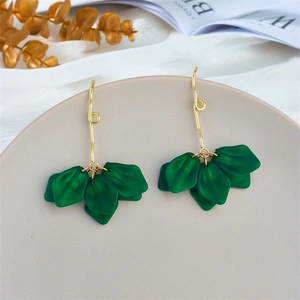 Macro shot of green petal leaf drop earrings with long gold ear hooks on a grey tray