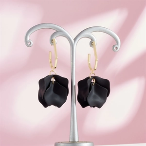 Detail of matte black multi-layered petal earrings with golden geometric hooks