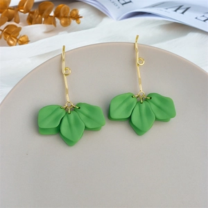 Detail shot of long gold earrings featuring layered green frosted leaf floral accents