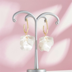 Detailed macro view of retro floral petal earrings with golden hexagonal studs and matte finish