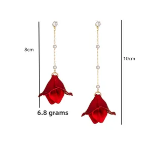 Detail of red petal drop earrings with gold chain, pearls, and cubic zirconia, 10cm long