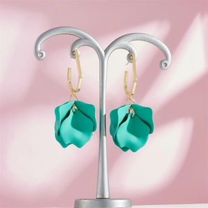 Close-up of mint green petal earrings with golden geometric hooks on display
