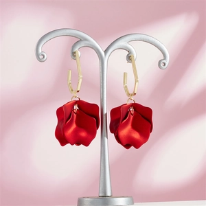 Vintage red flower petal drop earrings with gold geometric hooks on a jewelry stand