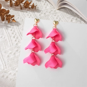 Macro view of triple-layered hot pink petal drop earrings with golden heart studs