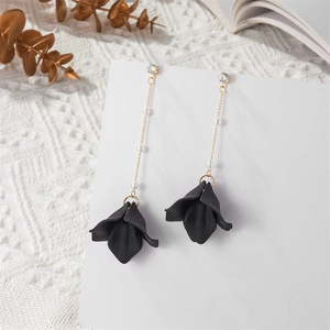 Detail of long tassel earrings featuring black petals, white pearls, and gold chains