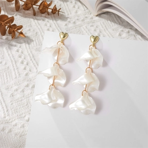 Detail of gold heart stud and layered pearlescent petal elements on long tassel earrings