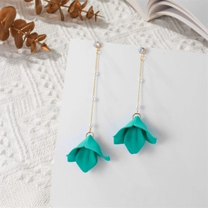 Detail of floral tassel earrings with green resin petals and elegant gold chain pearls